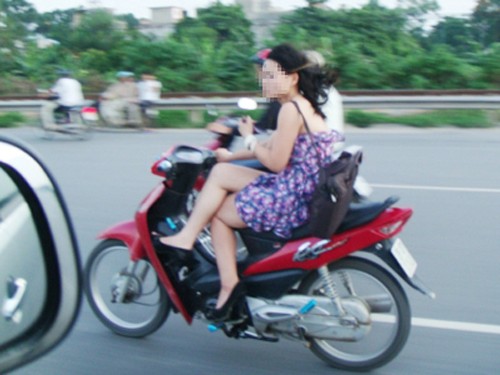 Thiếu nữ xinh đẹp vắt chân, đầu trần đi xe máy